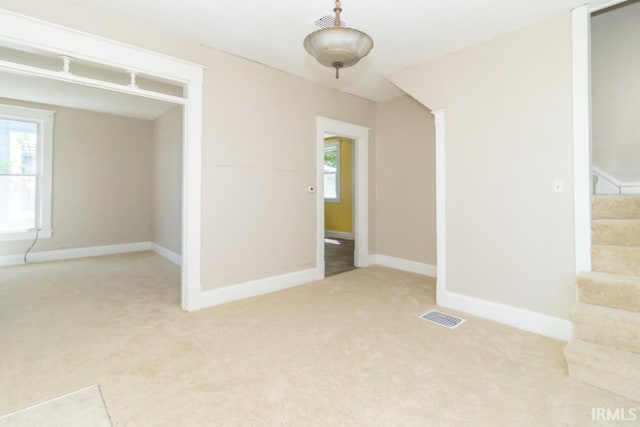 carpeted empty room with baseboards and stairs