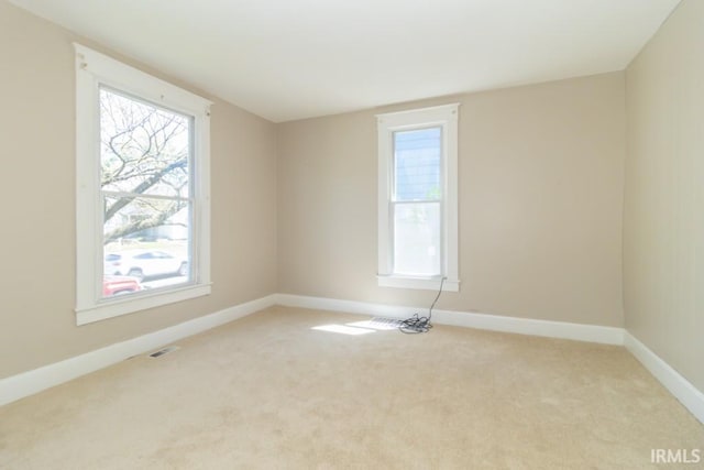 empty room featuring baseboards and light colored carpet