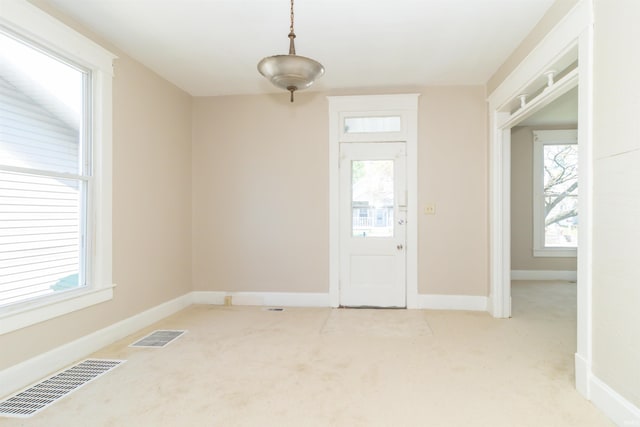 spare room with light colored carpet, plenty of natural light, and baseboards