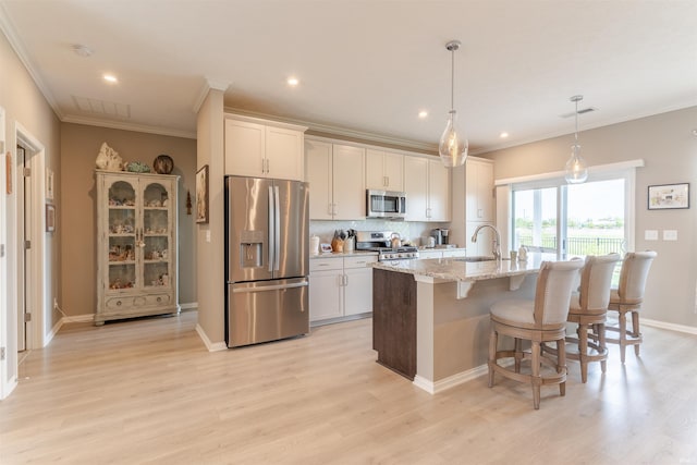 5512 Abbe Wood Dr, Newburgh, IN 47630 - kitchen with appliances with stainless steel finishes, a center island with sink, a breakfast bar, light wood finished floors, and ornamental molding