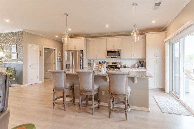 5512 Abbe Wood Dr, Newburgh, IN 47630 - kitchen featuring appliances with stainless steel finishes, a kitchen island with sink, ornamental molding, light wood-style floors, and a breakfast bar area