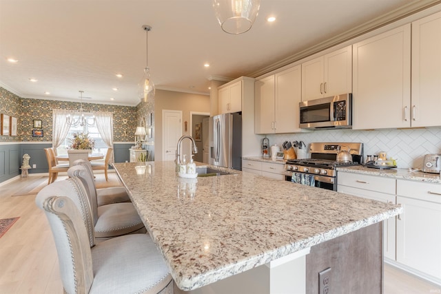 5512 Abbe Wood Dr, Newburgh, IN 47630 - kitchen with stainless steel appliances, crown molding, a sink, a kitchen island with sink, and light wood finished floors