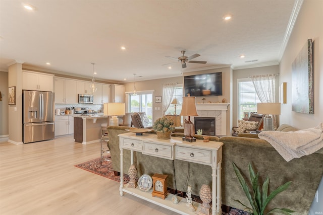 5512 Abbe Wood Dr, Newburgh, IN 47630 - living area featuring crown molding, light wood finished floors, plenty of natural light, a ceiling fan, and a tiled fireplace