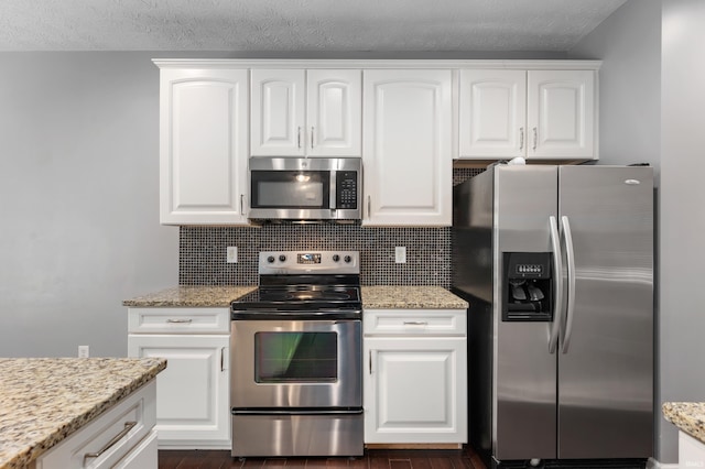 2378 The Springs Dr, Indianapolis, IN 46260 - kitchen featuring stainless steel appliances, decorative backsplash, white cabinetry, light stone counters, and a textured ceiling