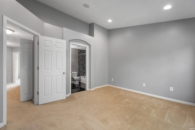 2378 The Springs Dr, Indianapolis, IN 46260 - unfurnished bedroom featuring light colored carpet, baseboards, arched walkways, recessed lighting, and connected bathroom