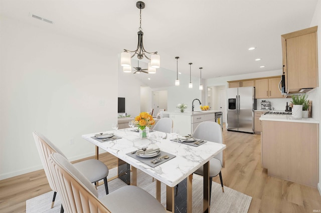 dining area with a chandelier, light wood-style flooring, recessed lighting, and baseboards