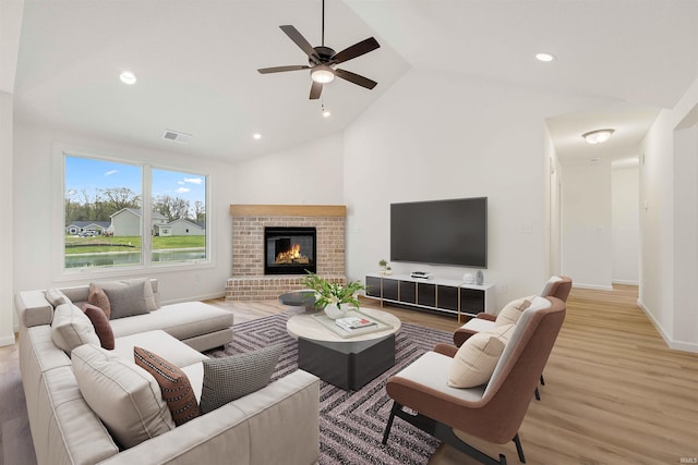 living area with wood finished floors, lofted ceiling, ceiling fan, baseboards, and a brick fireplace
