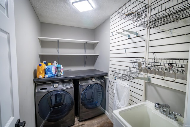 clothes washing area with independent washer and dryer, a textured ceiling, and wood finished floors