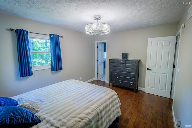 bedroom featuring dark wood-style floors, a textured ceiling, a chandelier, and baseboards