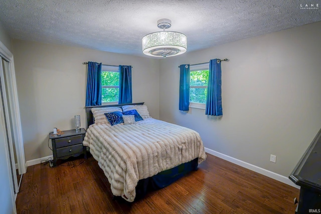 bedroom featuring wood finished floors, baseboards, multiple windows, and a textured ceiling