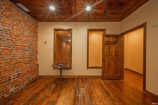 28 N Washington St, Knightstown, IN 47362 - empty room with an ornate ceiling, hardwood / wood-style flooring, brick wall, and baseboards