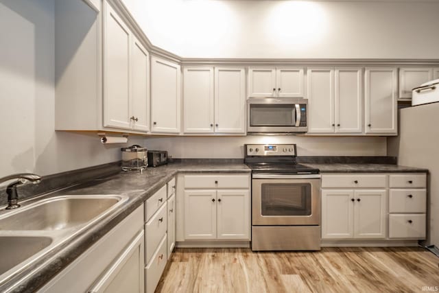 28 N Washington St, Knightstown, IN 47362 - kitchen with appliances with stainless steel finishes, a sink, light wood-type flooring, and dark countertops