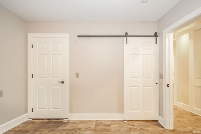 28 N Washington St, Knightstown, IN 47362 - unfurnished bedroom featuring a barn door, baseboards, and light wood-style flooring