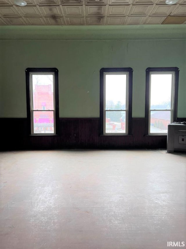 28 N Washington St, Knightstown, IN 47362 - spare room featuring plenty of natural light, an ornate ceiling, a wainscoted wall, and concrete floors