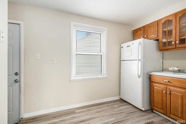 1803 W Dubail St, South Bend, IN 46613 - kitchen featuring freestanding refrigerator, brown cabinetry, light wood-style floors, and glass insert cabinets