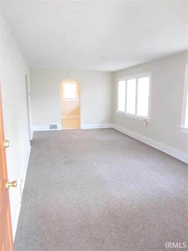 carpeted empty room featuring healthy amount of natural light and baseboards