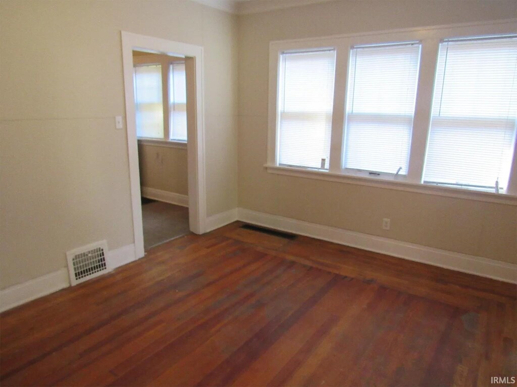 unfurnished room with dark wood-type flooring and baseboards
