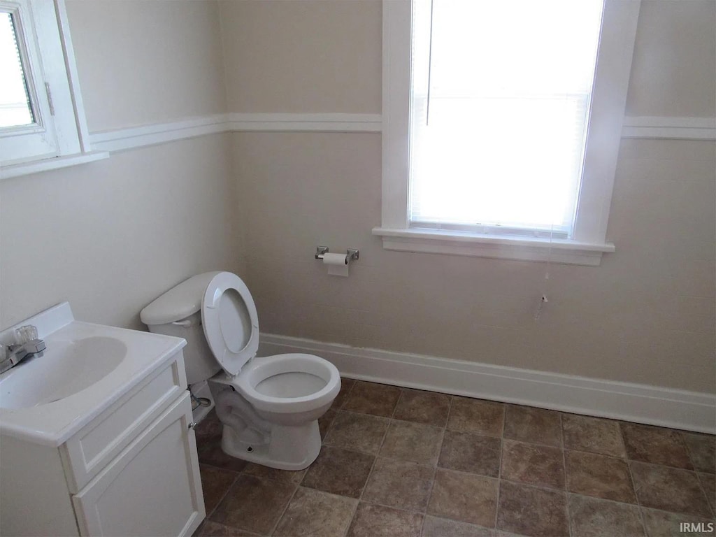 half bath featuring toilet, vanity, and baseboards