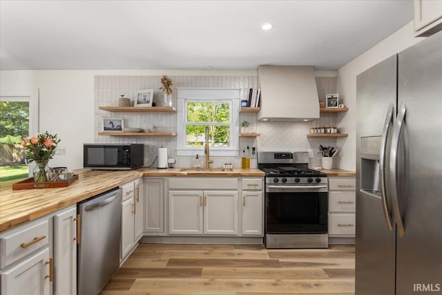 736 Paradise Ave, Lafayette, IN 47905 - kitchen with appliances with stainless steel finishes, open shelves, butcher block countertops, wall chimney exhaust hood, and backsplash
