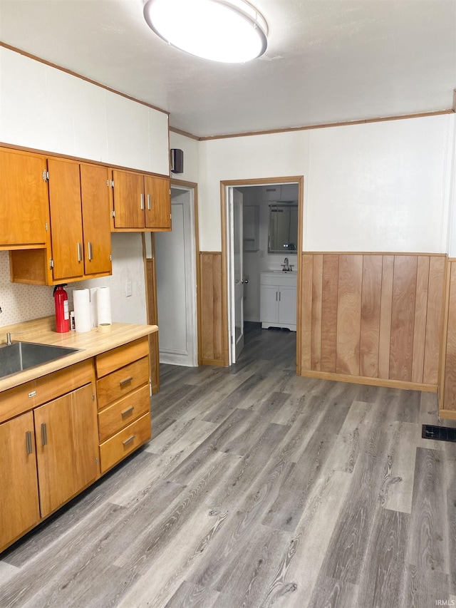 710 N Union St, Union City, IN 47390 - kitchen with a sink, a wainscoted wall, wood finished floors, brown cabinetry, and light countertops