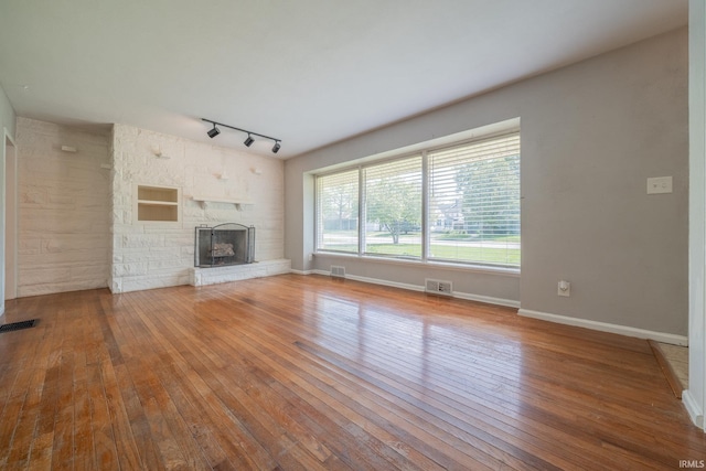 323 N Berkley Rd, Kokomo, IN 46901 - unfurnished living room featuring hardwood / wood-style flooring, rail lighting, a fireplace, and baseboards