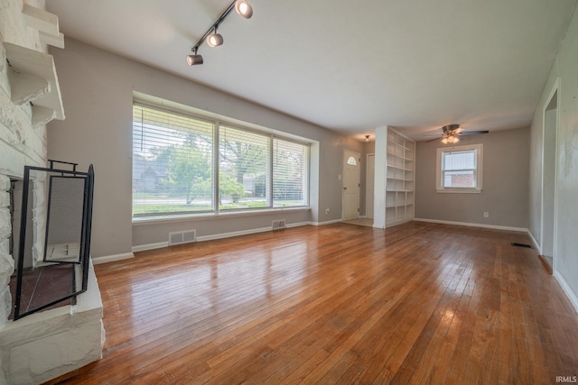323 N Berkley Rd, Kokomo, IN 46901 - unfurnished living room featuring a fireplace, a ceiling fan, wood-type flooring, rail lighting, and baseboards