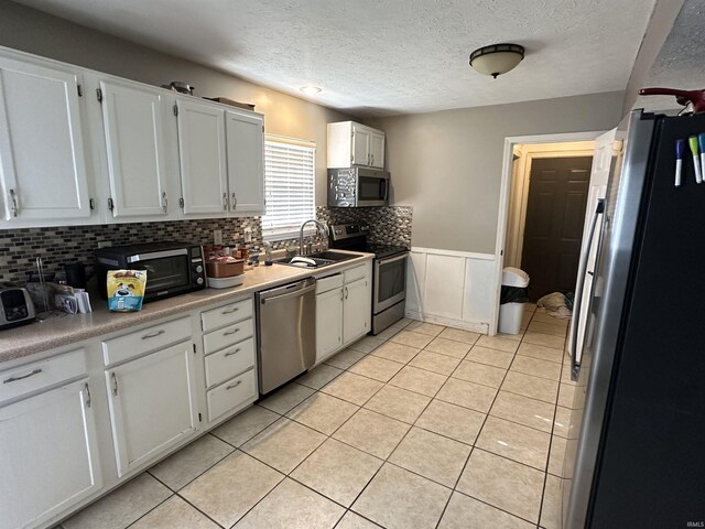 4909 Leicester Way, West Lafayette, IN 47906 - kitchen with appliances with stainless steel finishes, a sink, tasteful backsplash, white cabinetry, and a textured ceiling