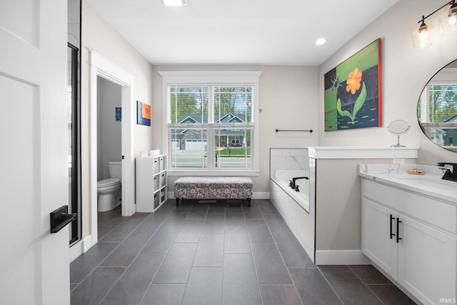 bathroom with toilet, vanity, baseboards, a garden tub, and recessed lighting