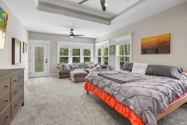 carpeted bedroom with access to exterior, a raised ceiling, multiple windows, crown molding, and ceiling fan