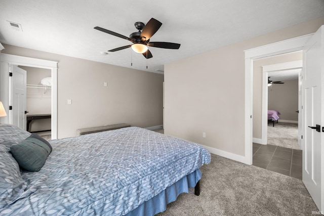 carpeted bedroom with baseboards, ceiling fan, tile patterned flooring, a spacious closet, and a closet