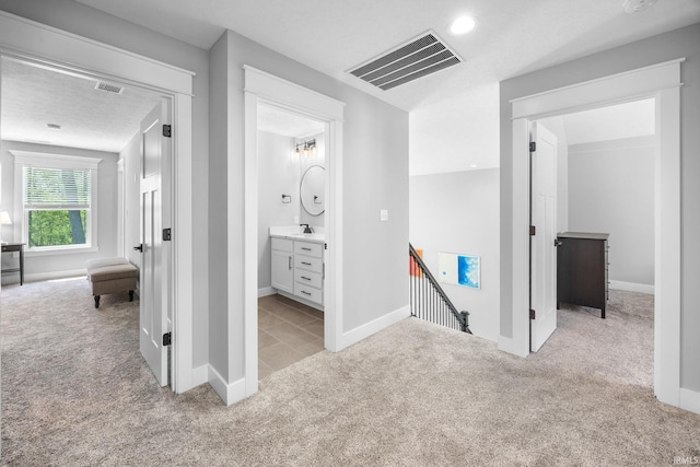corridor with an upstairs landing, light colored carpet, a sink, baseboards, and recessed lighting
