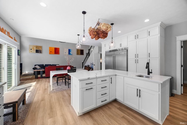 kitchen featuring a sink, stainless steel built in fridge, light wood-style flooring, white cabinets, and recessed lighting