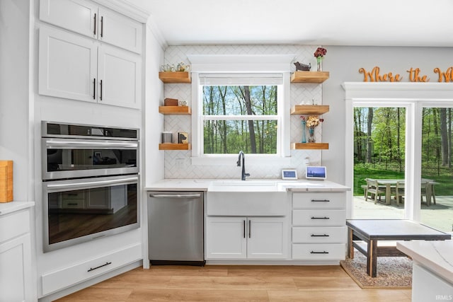 kitchen featuring open shelves, stainless steel appliances, a sink, and decorative backsplash