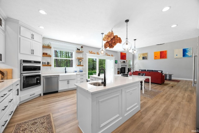 kitchen featuring appliances with stainless steel finishes, a sink, open shelves, recessed lighting, and open floor plan