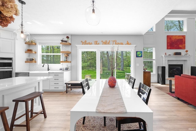 dining space with plenty of natural light, light wood-type flooring, a fireplace, and recessed lighting