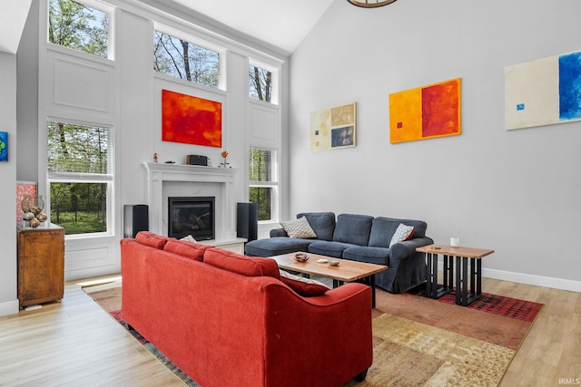 living room featuring high vaulted ceiling, plenty of natural light, wood finished floors, and a fireplace