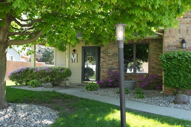 property entrance featuring fence and brick siding