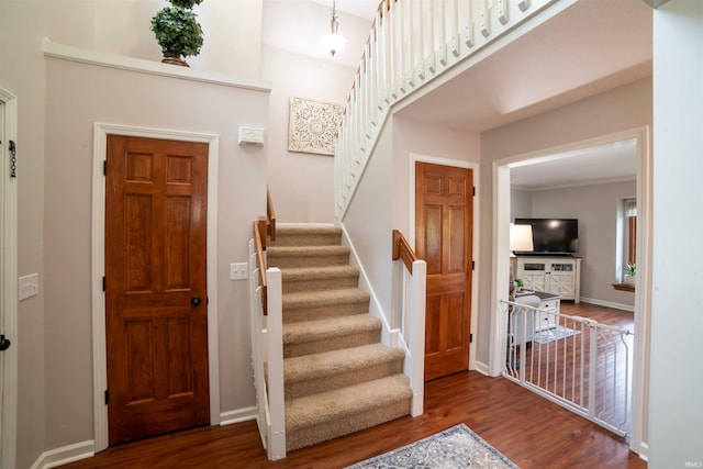 entrance foyer with stairs, wood finished floors, and baseboards