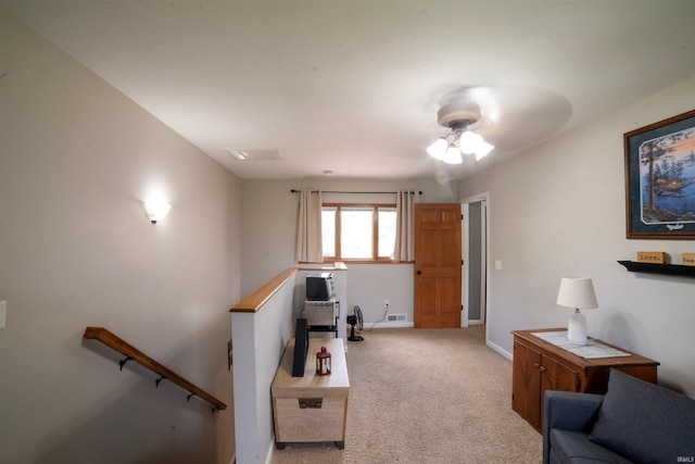 living area featuring light carpet, a ceiling fan, and baseboards