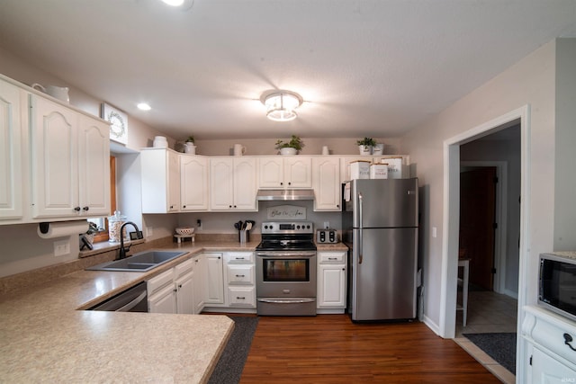 kitchen with appliances with stainless steel finishes, a sink, under cabinet range hood, white cabinets, and recessed lighting