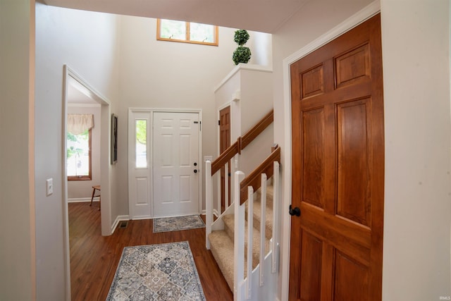 foyer with dark wood-type flooring, baseboards, and stairs