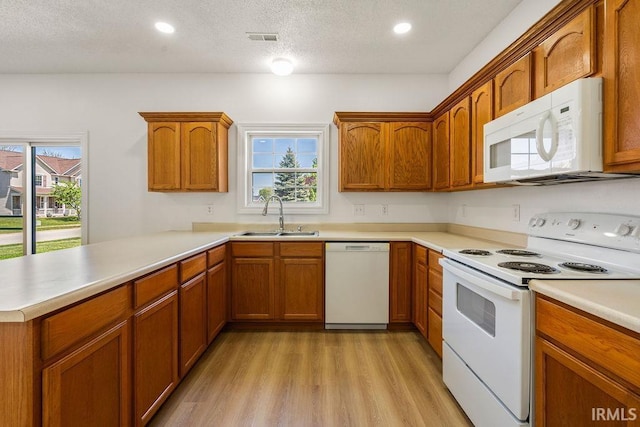 1041 Spring Mill Dr, Kokomo, IN 46902 - kitchen with white appliances, a sink, light wood-style floors, a peninsula, and brown cabinetry