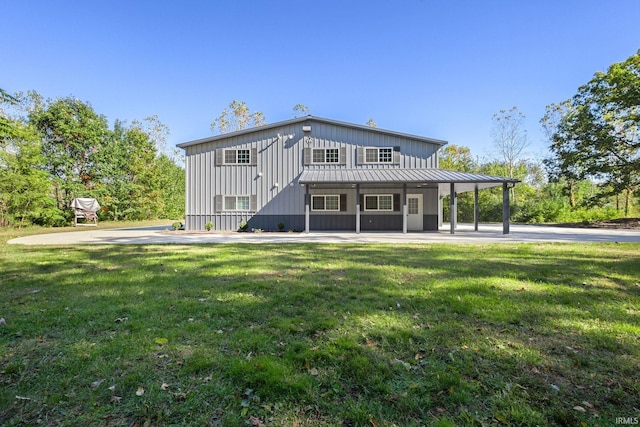 back of property featuring board and batten siding, a lawn, a standing seam roof, and metal roof