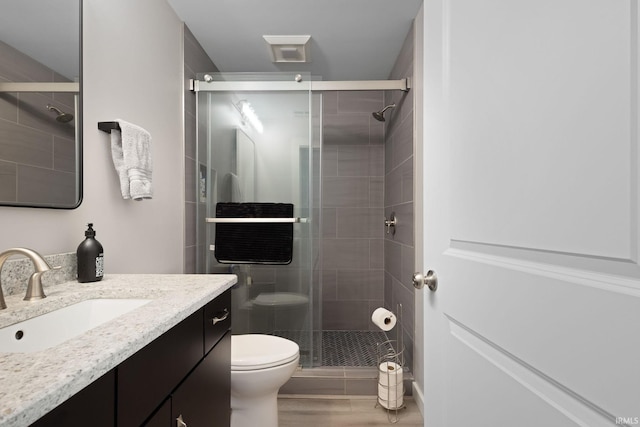 full bath featuring a shower stall, toilet, vanity, and wood finished floors