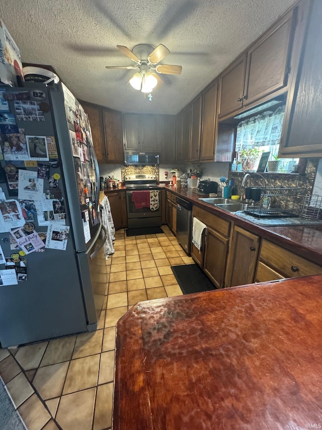 515 E Washington St, Attica, IN 47918 - kitchen with stainless steel appliances, dark countertops, a ceiling fan, light tile patterned floors, and a textured ceiling