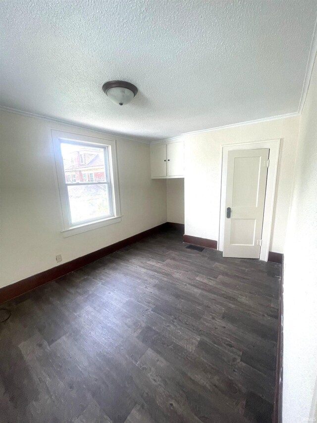 1307 High St, Logansport, IN 46947 - spare room with dark wood finished floors, a textured ceiling, ornamental molding, and baseboards
