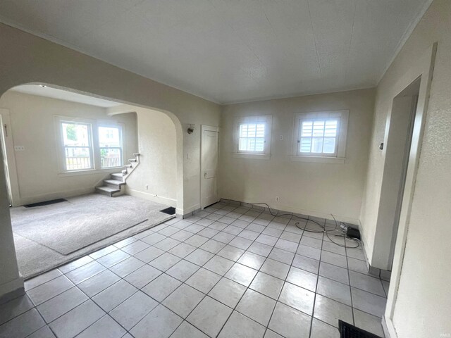 1307 High St, Logansport, IN 46947 - spare room featuring arched walkways, stairs, crown molding, light tile patterned floors, and baseboards