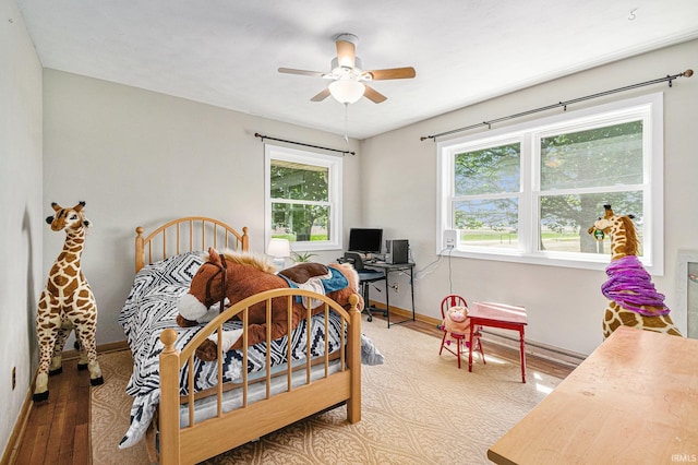 bedroom with baseboard heating, baseboards, wood finished floors, and ceiling fan