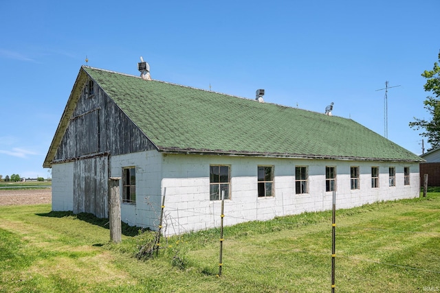 view of side of home featuring roof with shingles and a yard