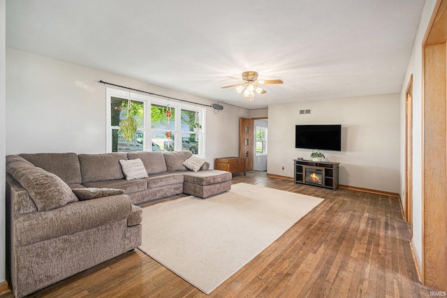 living area featuring a ceiling fan, wood-type flooring, a fireplace, and baseboards